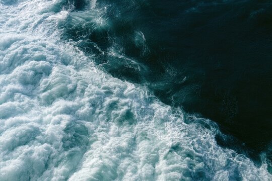 Turbulent, foamy white water meets deep, dark ocean depths