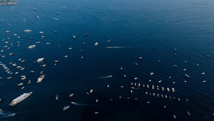 Naklejka premium Boats and yachts scattered across the vast dark blue mediterranean sea near the amalfi coast, italy, captured from an aerial perspective during summer