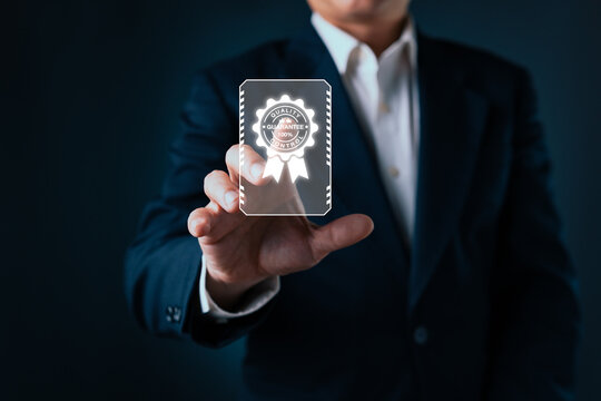 Businessman touching a virtual quality control certificate badge to ensure standard service certification, product assurance, and premium business guarantee in dark studio background.