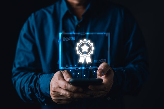 Close up of businessman holding smartphone with virtual top quality guarantee certificate badge icon for high standard service, premium product assurance, and business success in dark studio.