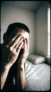 Man Hiding Face In Hands Feeling Despair Melancholy In Bedroom