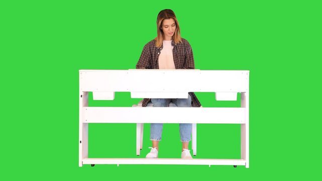 Aspiring young woman studies playing the electric piano on a Green Screen, Chroma Key.