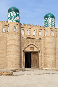 Kunya Ark citadel entrance gate with twin turquoise-domed towers in Khiva Uzbekistan. Iconic fortified gateway of Ichan Kala with ornamental brickwork and carved wooden doors, ideal for travel.