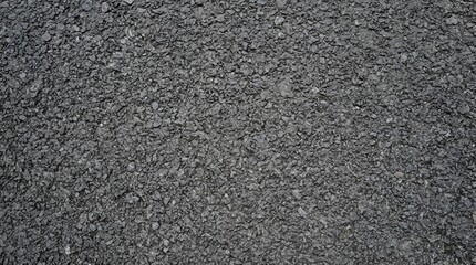 Fototapeta premium Rough asphalt road surface texture with dark grey gravel and small stones creating a coarse and gritty pattern for urban infrastructure