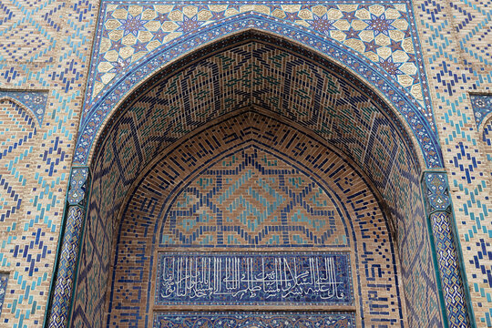 Ornate pointed arch of Bibi Khanum Mosque in Samarkand with intricate tilework and Arabic calligraphy. Ideal for travel publications, cultural heritage materials, and architectural references.