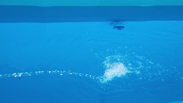 Filling a swimming pool with water. Blue water background. Home pool maintenance. Minimal, copy space.

