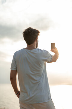 vertical Remote worker taking sunset photo with smartphone
