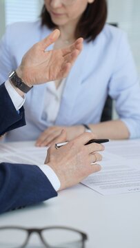 Businessmen and woman negotiating terms of a contract, discussing agreement details on paperwork, preparing to sign legal documents to finalize a professional deal