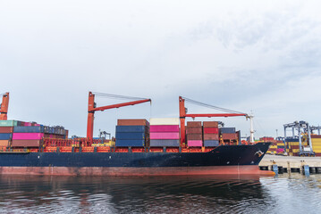 Naklejka premium Container ship berthed alongside a container terminal during cargo operations.