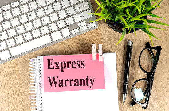 Express warranty concept on notepad with keyboard eyeglasses and pen on office desk representing legal guarantee consumer protection