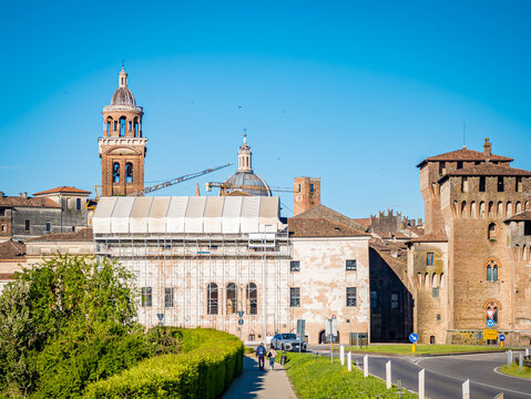 Mantova cityscape features historic buildings like Palazzo Ducale and Castel San Giorgio. Showcasing Renaissance and medieval architecture under a clear blue sky