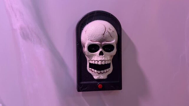 Hand pressing Halloween skull decoration, tongue pops out and eyes light up
