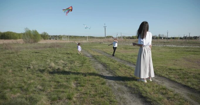 Children with mother flying a kite. Family spend time together on nature. 4K 10-bit