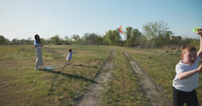 Children with mother flying a kite. Family spend time together on nature. 4K 10-bit