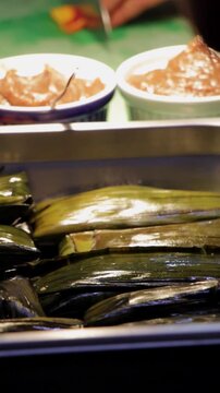 Charola con tamales oaxaque&ntilde;os en cocina profesional. Paneo sobre tamales de hoja de pl&aacute;tano reci&eacute;n preparados. Tamales oaxaque&ntilde;os listos para servirse en restaurante. Comida tradicional mexicana .