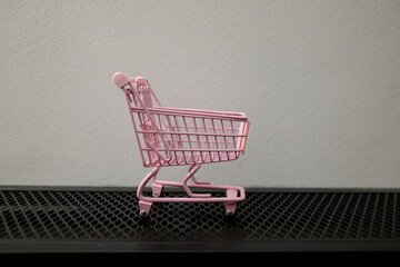 Empty pink toy shopping cart on black surface with copy space, shopping concept © Stanislava