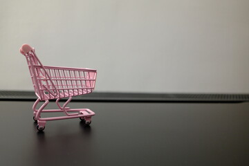 Empty pink toy shopping cart on black surface with copy space, shopping concept © Stanislava