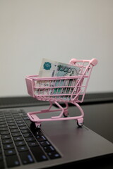 Pack of 1,000 Russian ruble banknotes in pink toy shopping cart on open laptop, online shopping and e-commerce concept © Stanislava