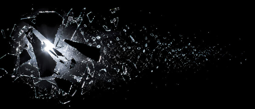 Sharp shards of broken glass exploding and flying through the air, isolated on a black background.