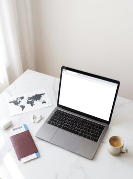 Business traveler desk workspace with laptop passport and map for travel planning, passport