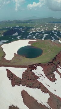 Vertical Video of Scenic Volcanic Crater Pond with Turquoise Water and Patchy Snow