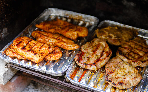 Putensteaks und Schweinenackensteaks werden auf Holzkohlebriketts gegrillt.