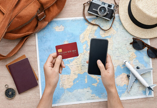 Travel Planning Concept with Smartphone and Credit Card on European Map Surrounded by Passport, Camera, Hat, Bag, and Airplane Model for Vacation Booking and Tourism Design