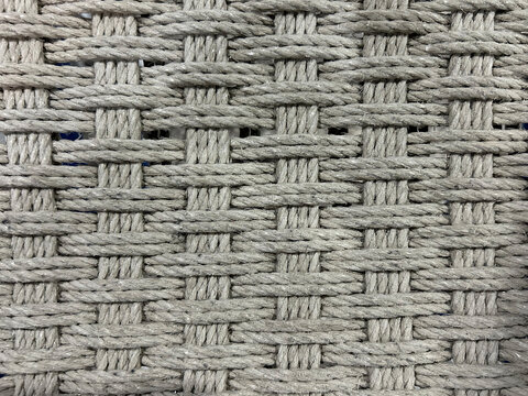 Close-up of a woven gray rope texture with an intricate braided pattern. Durable synthetic fiber surface forms a geometric abstract background, ideal for design, textiles, and d&eacute;cor.