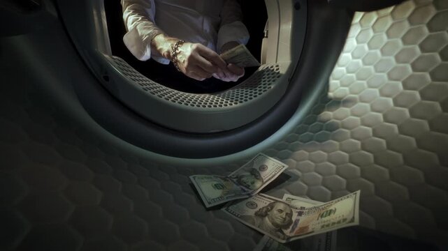 Conceptual video of an unrecognisable Caucasian man wearing a white shirt placing US dollar banknotes in a washing machine with his hands and taking them out in slow motion. Money Laundering Concept