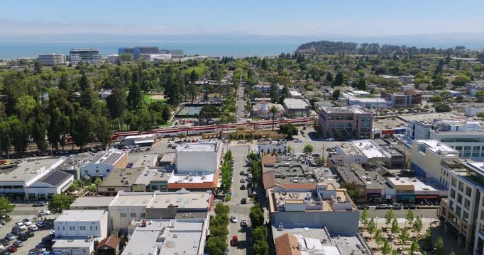 Burlingame California - Aerial Approach Over Burlingame Ave Towards Busy Train Station with Cars and Pedestrians Passing By