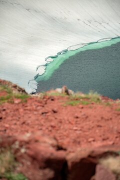 Aerial View of Alpine Crater Lake Edge with Emerald Water Transitioning to Deep Blue Deep