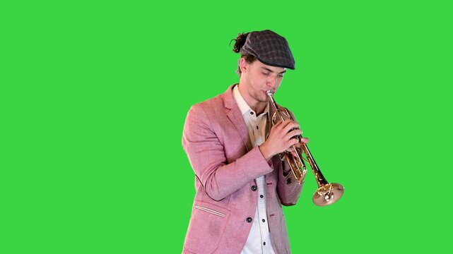 Young gifted street musician plays the trumpet masterly on a Green Screen, Chroma Key.