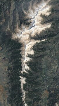 Aerial view on mountain ridge covered with snow. Camera is zooming in, rotating clockwise. Vertical video. Animation based on image by NASA