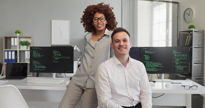 Programmer developers team man woman coding teamwork office. Two colleagues by monitors with code convey modern collaboration and productivity. Ideal for corporate tech, training and hiring.