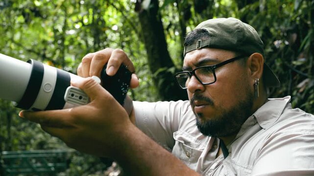 Concentrated wildlife photographer adjusting camera settings with a telephoto lens. Man exploring the lush rainforest of Arenal Volcano National Park