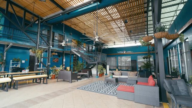 Stylish interior of a contemporary hostel in Costa Rica, featuring a vibrant common area with comfortable seating and lush green plants