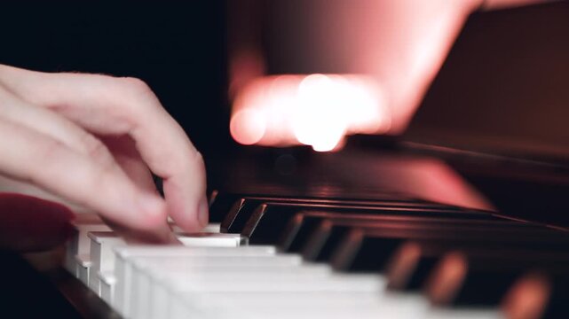 Pianist playing classical music on piano keyboard. Man hand pressing piano key during musical performance. Close up of musician practicing melody in dark room.