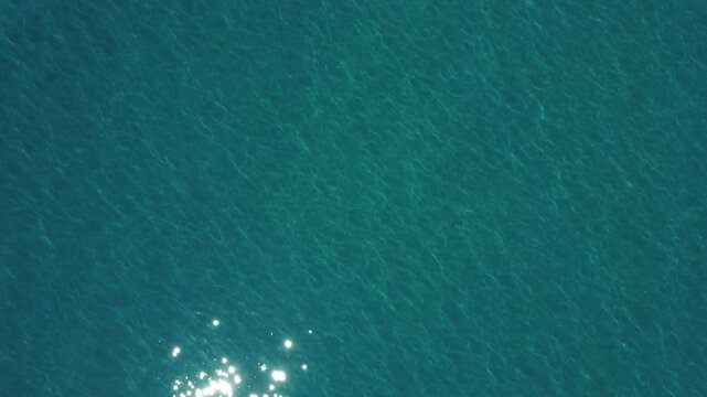 Aerial view of clear turquoise sea water with sunlight reflections