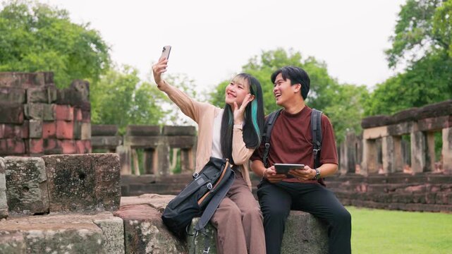 Excited travelers pointing at high temple tower holding travel map