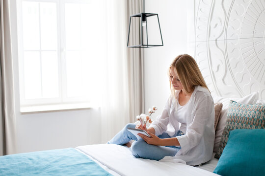 Woman relaxing in bed near window. Girl journaling, drawing. Art therapy, self compassion, female wellness, morning routine in cozy home. Slow living, mindfulness, analog lifestyle, digital detox