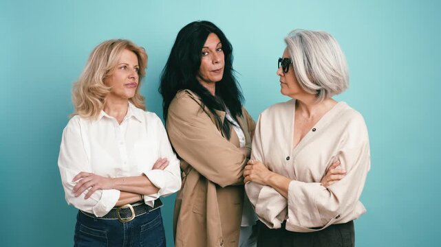 Three different mature women standing together with confidence. Stylish ladies showing their attitude and personality on a solid background
