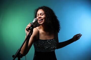 Obraz premium Professional singer with microphone performing on color background