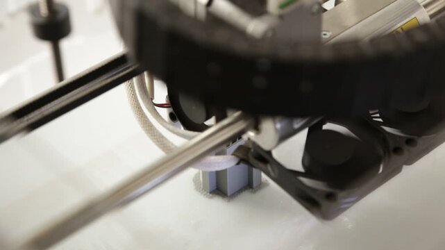 Closeup of a robotic manufacturing machine with a circular drag chain, motors, and wiring. hree dimensional printer during work, 3D printing in action.