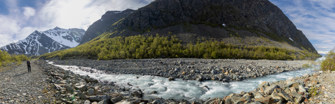 panoramic view of woman hiking to glacier Koppangsbreen and Tafeltinden near the small village of Koppangen in northern Norway on the western side of the Lyngen Alps on the Lyngenfjord