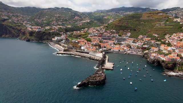 Madeira island, Camara de Lobos drone panoramic flight from right to left revealing the coastal village, scenic bay and colorful fishing boats, Portugal cinematic footage 4k