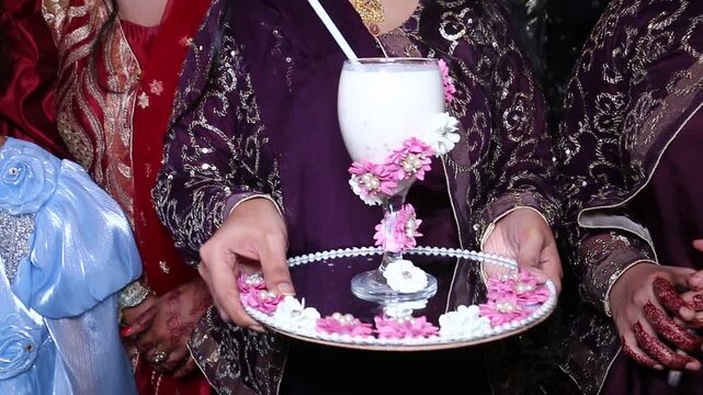 Woman holding tray with decorated milk drink during ceremony with presenting floral decorated video hands presenting during celebration middle eastern