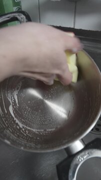 plano cercano de una mano de una chica lavando una olla en la cocina