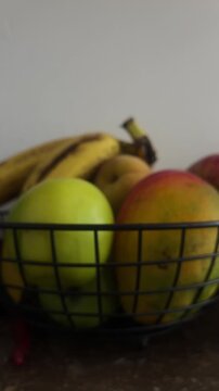 Hand picking red apple from wire basket of fresh fruit