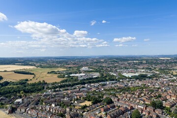 Fototapeta premium Aerial photo overlooking Mexborough in South Yorkshire England showing residential housing industrial estates farmland and surrounding countryside beneath a bright blue summer sky with scattered cloud