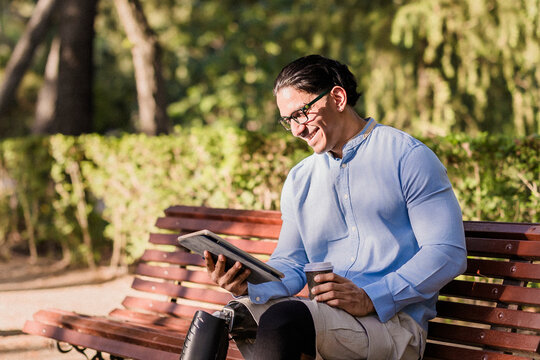 Latino disabled worker relaxing with tablet in park